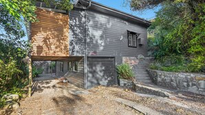 A modern two-story house with a garage, a stone retaining wall, and a well-maintained garden. - Beau Soleil, 28 East Street (Crescent Head)