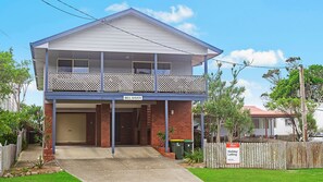 A two-story building with a balcony, a garage, and a sign indicating holiday letting.