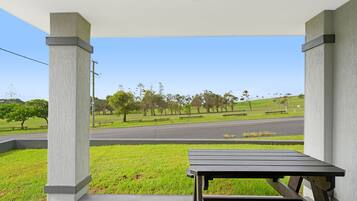 A covered outdoor seating area with a view of a park and road.