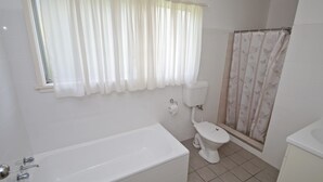 Un baño con bañera, inodoro y cortina de ducha.