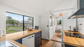 A modern kitchen with a dishwasher, wooden countertops, a sink, and a view of the backyard.