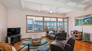 A living room with a television, seating, a coffee table, and a view of the outdoors.
