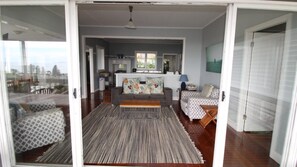 A spacious living area with a sofa, a patterned rug, and a view of the kitchen through an open door.
