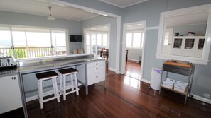 A kitchen with a large island, wooden stools, a television, and a view of the outdoors.