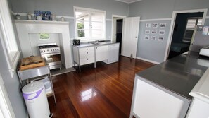 A kitchen with a stove, sink, and cabinets, wooden flooring, and a window.