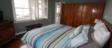 A bedroom with a bed, wooden dresser, bench, and a wardrobe.