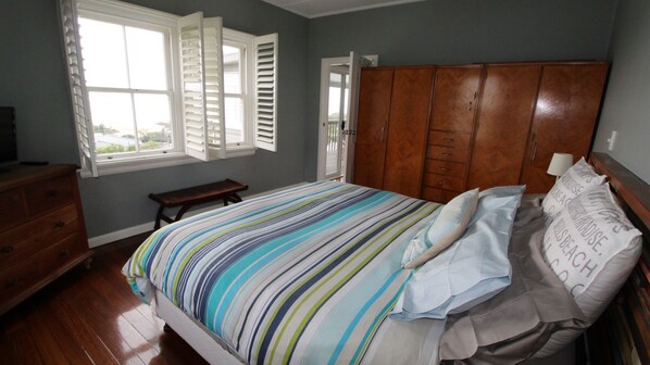 A bedroom with a bed, wooden dresser, bench, and a wardrobe.