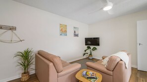 A living room with two sofas, a coffee table, a TV, and a ceiling fan.
