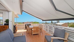 Varanda coberta com mesa e cadeiras, com vista para uma paisagem deslumbrante.