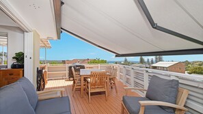 Una terraza techada al aire libre con una mesa y sillas, con vistas a un paisaje pintoresco.