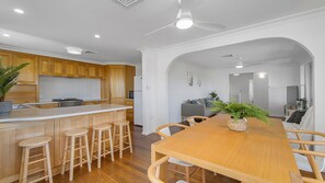 Una cocina moderna con armarios de madera, una isla central con taburetes y un comedor con mesa y sillas de madera.
