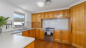 A modern kitchen with wooden cabinets, a stainless steel stove, and a large window.