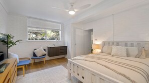 Un dormitorio con cama, escritorio, silla, radiador y ventana con persianas.