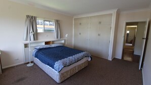 A bedroom with a bed, a wardrobe, a window with curtains, and a carpeted floor. - Horizons 7 East Street, Crescent Head (Crescent Head)