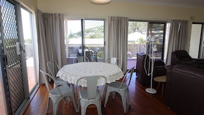 A room with a round table, chairs, a sofa, and a balcony with a view. - Horizons 7 East Street, Crescent Head (Crescent Head)