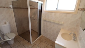 A bathroom with a glass-enclosed shower, a toilet, and a sink with a mirror above it. - Horizons 7 East Street, Crescent Head (Crescent Head)