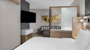 A modern hotel room with a large bed, a flat-screen TV, a sofa, a wooden desk, and artwork on the walls. - SpringHill Suites by Marriott Riverside Redlands (Redlands)