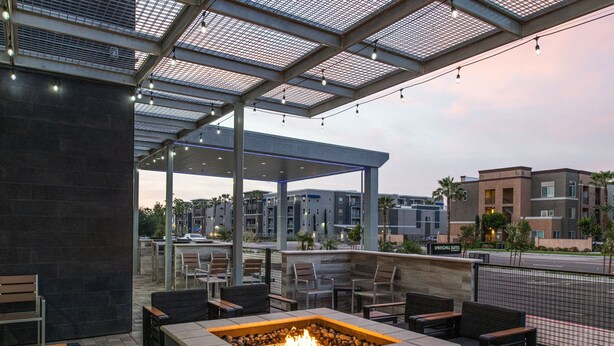 An outdoor patio area with a fire pit, seating, and a covered section with a view of the cityscape. - SpringHill Suites by Marriott Riverside Redlands (Redlands)