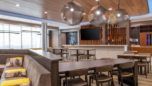 A modern hotel lobby with a bar area, seating arrangements, and a large flat-screen TV mounted on the wall. - SpringHill Suites by Marriott Riverside Redlands (Redlands)