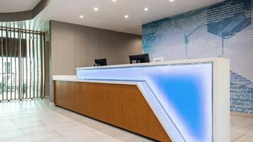 Un mostrador de recepción moderno con detalles de madera y un panel iluminado en azul.