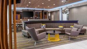 A modern lobby with a sectional sofa, armchairs, a small coffee table, and a TV screen. - SpringHill Suites by Marriott Riverside Redlands (Redlands)