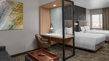 Een hotelkamer met een bureau, twee bedden, een stoel, een dienbladtafeltje en een groot raam.