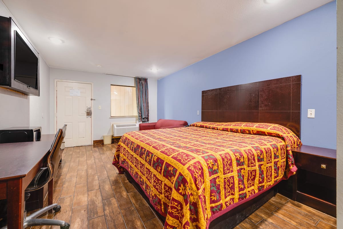A bedroom with a large bed, a desk, and a chair.