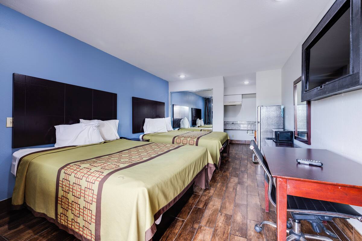 A hotel room with two beds, a desk, and a television.