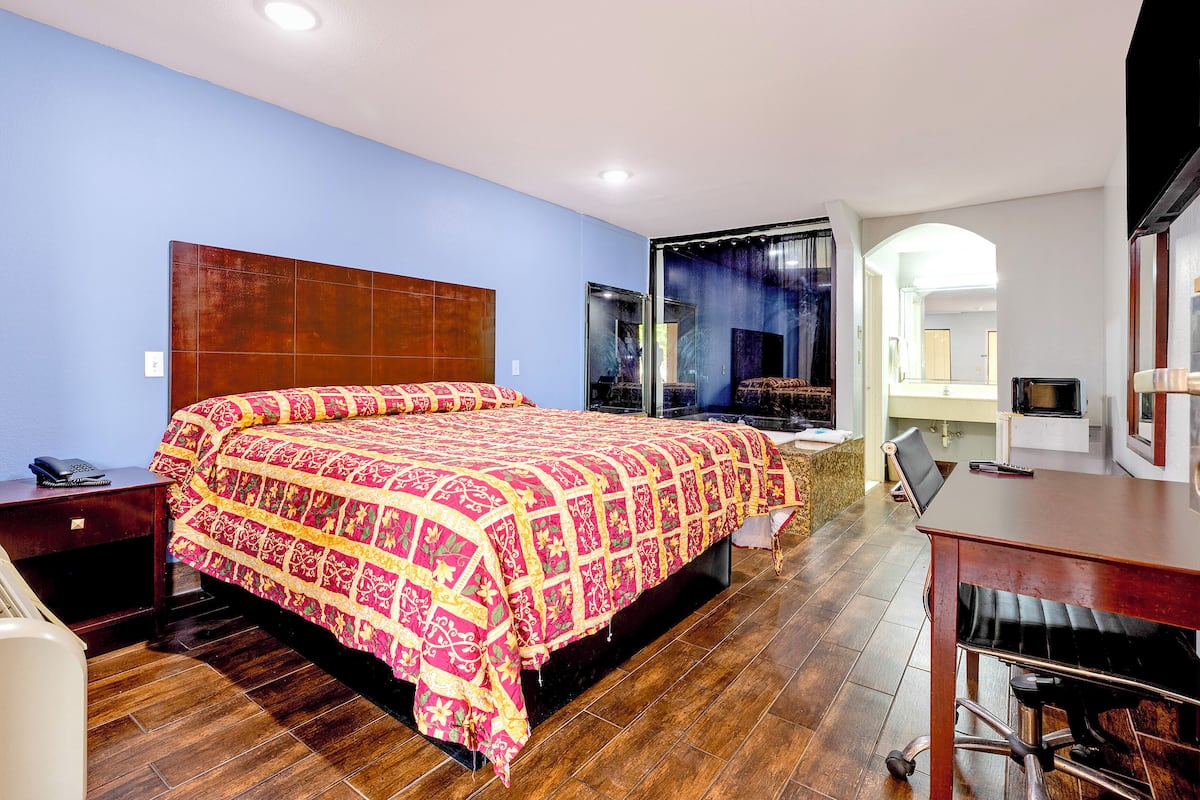 A hotel room with a large bed, a desk, and a chair.