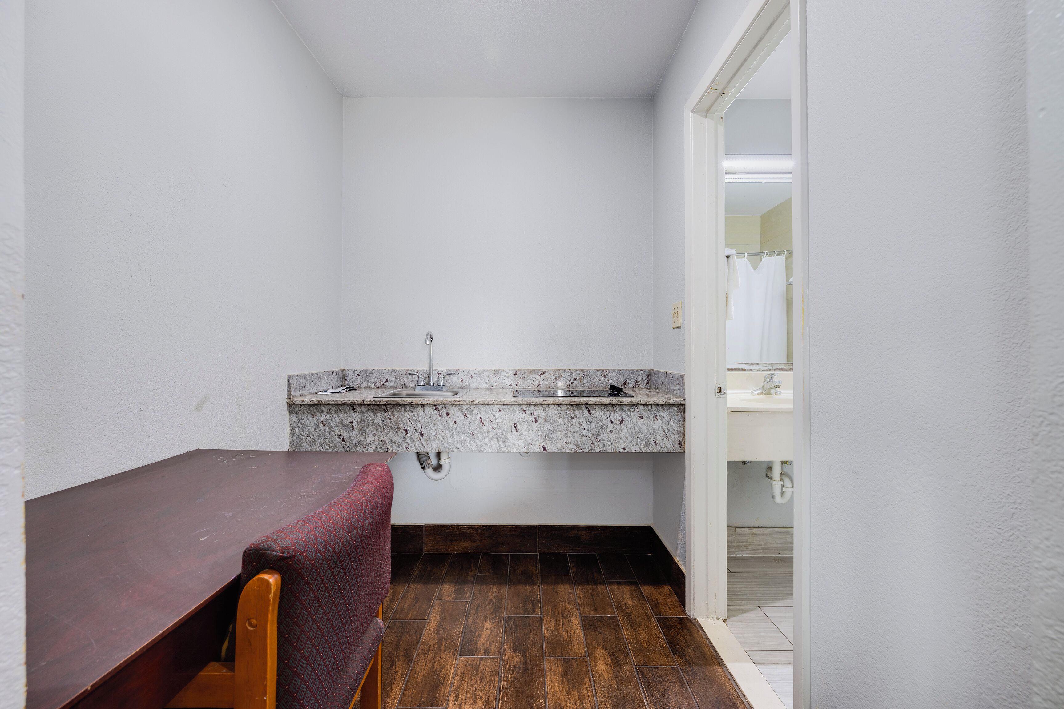 Un baño pequeño con lavamanos, espejo y banco de madera.