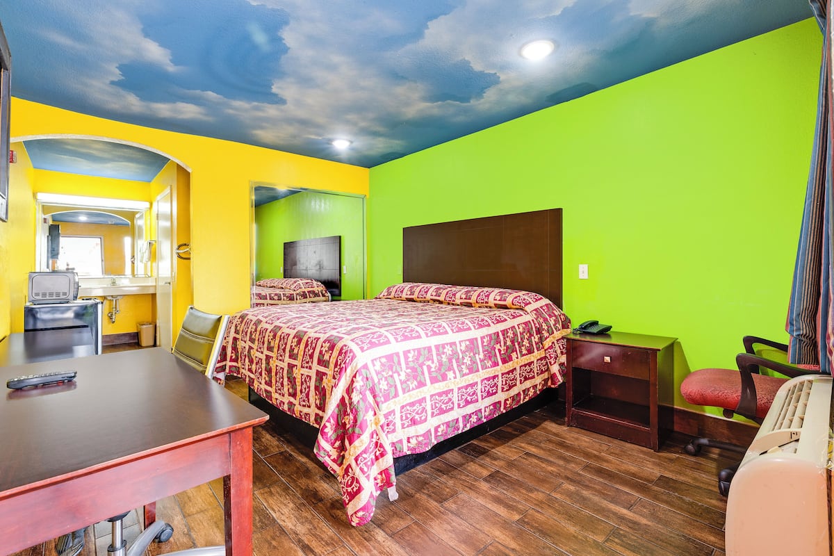 A room with a bed, desk, chair, and a television.