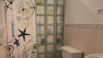 A bathroom with a toilet, sink, and shower area.