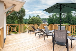 Relax on the deck with a clear view of the lush landscape, surrounded by a pergola and comfortable seating.
