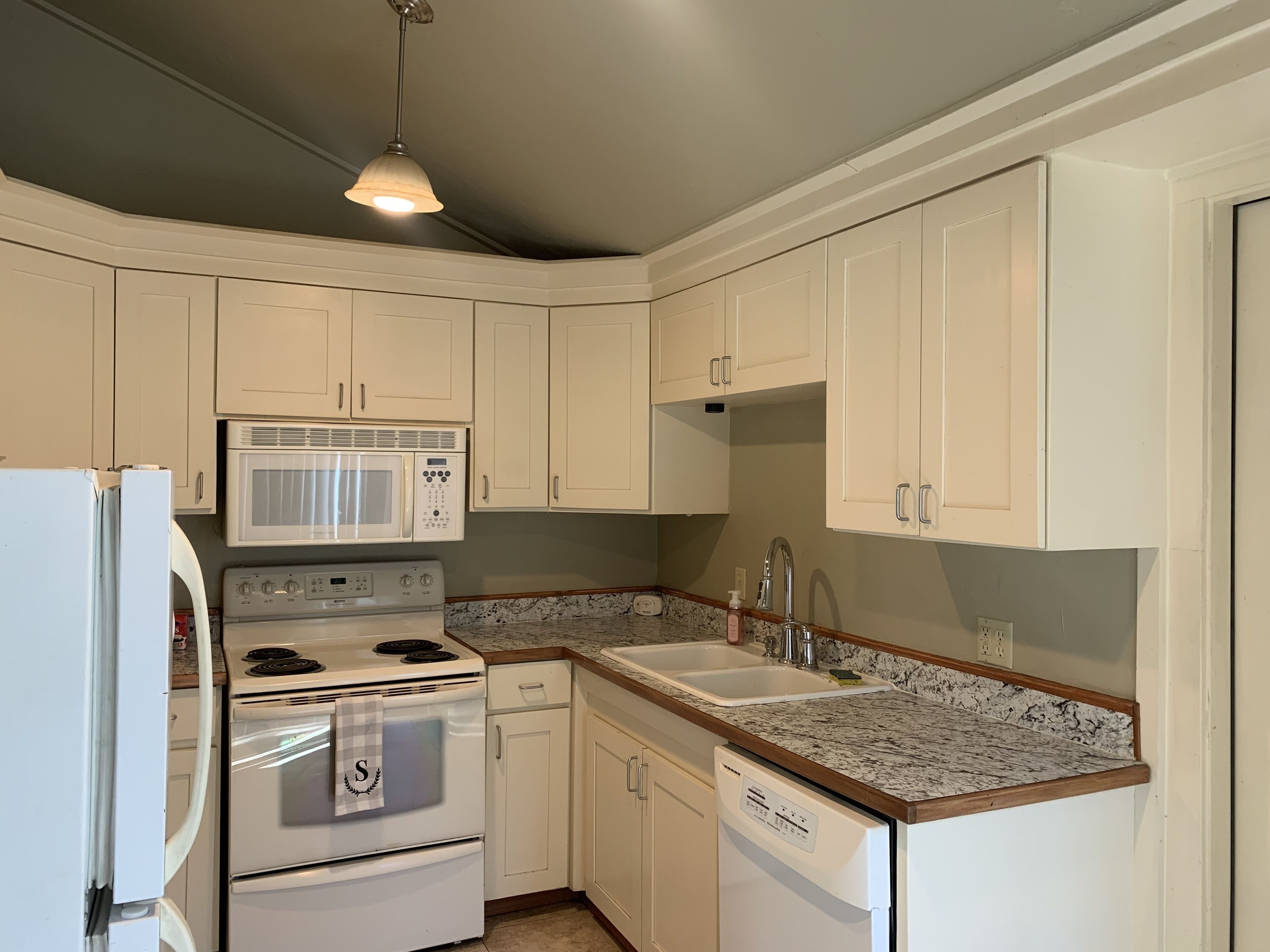 A kitchen with white cabinets, a microwave, stove, dishwasher, and granite countertops.