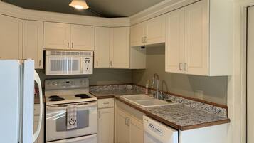 A kitchen with white cabinets, a microwave, stove, dishwasher, and granite countertops.
