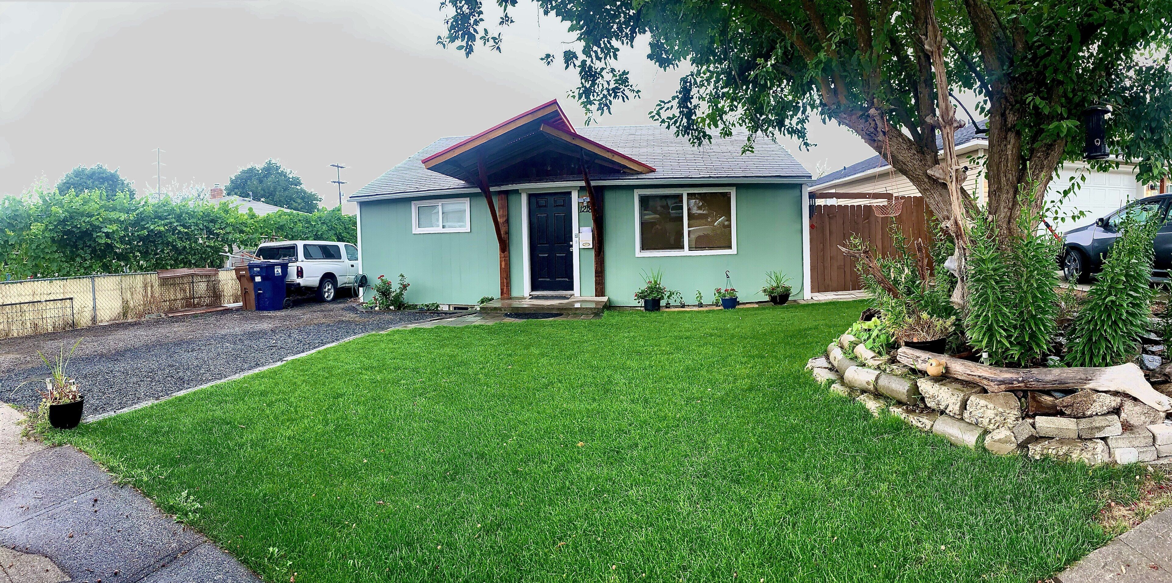 A single-story house with a green lawn, a front porch, and a driveway.
