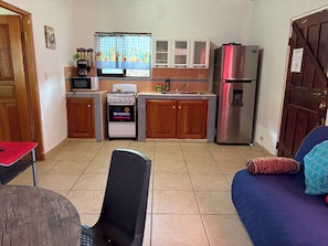 A compact kitchen with a stove, microwave, and refrigerator. There is a dining area with a table and a chair. - Cabañas Mountain View, near to the national park Volcan Baru (Volcán)