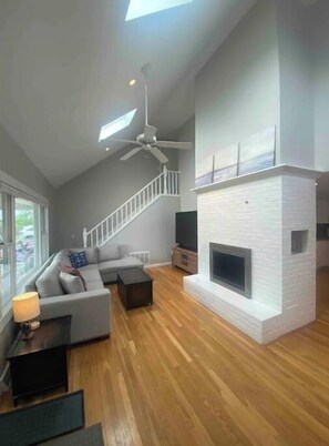 Relax in a spacious living area with a high ceiling and fireplace, surrounded by a comfortable sectional sofa and staircase.