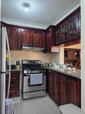 A kitchen with dark wooden cabinets, stainless steel appliances, and a granite countertop.