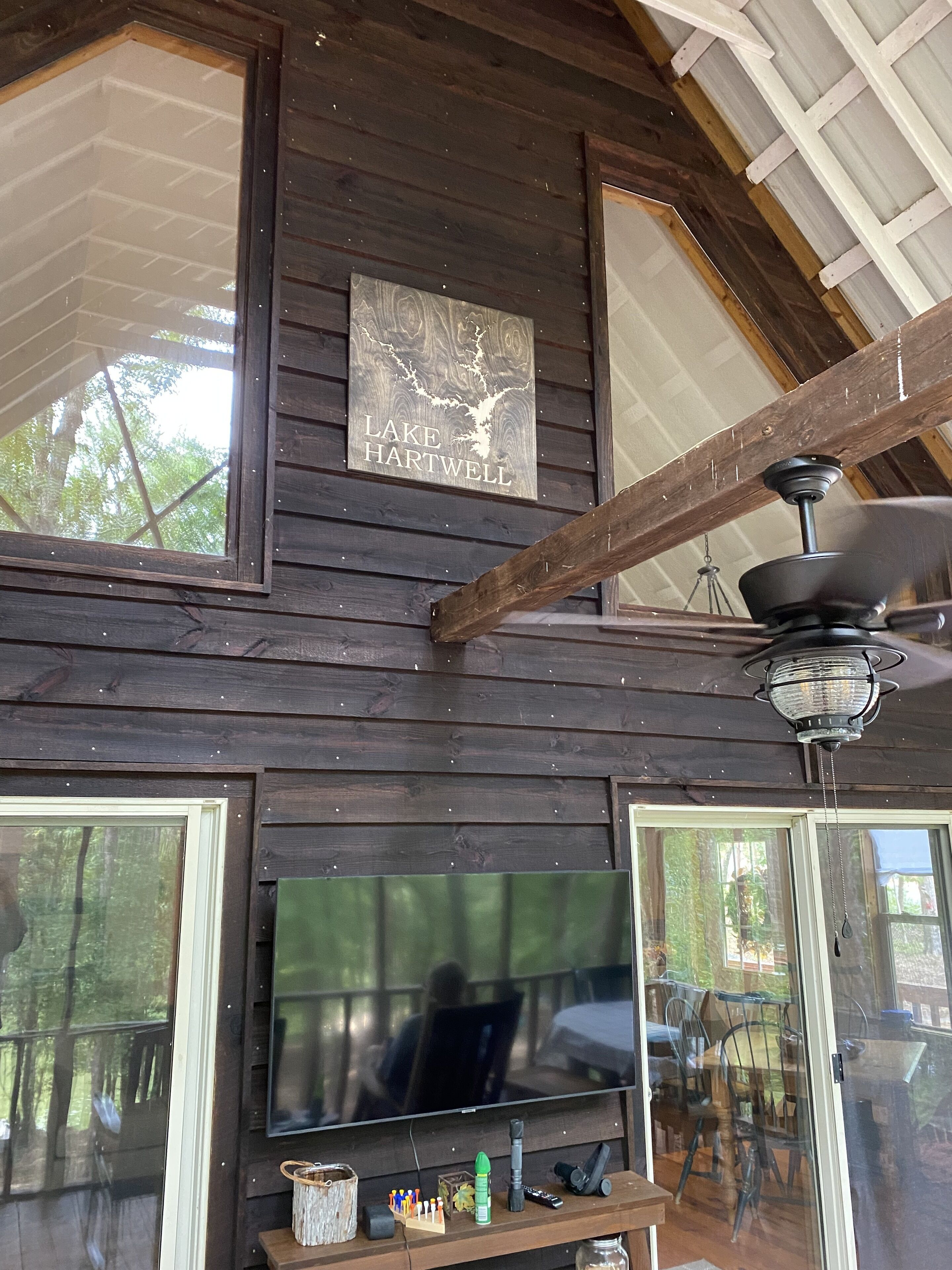 Ein Ferienhausinnenraum mit Holzfassade, einem fest installierten Fernseher und einem Deckenventilator.