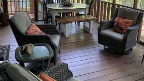 Eine überdachte Terrasse im Freien mit Korbmöbeln, einem Tisch und Stühlen.