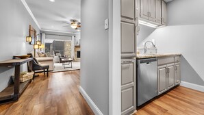 Una cocina moderna con electrodomésticos de acero inoxidable, un comedor con mesa y sillas de madera, y una sala de estar con sofá y mesa de centro.