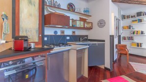 Una cocina moderna con lavavajillas, estufa y armarios de madera. Hay estanterías y una alfombra en la habitación.