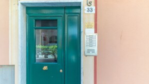 Puerta verde con ventana, buzón y un letrero con el número 33 en un edificio.