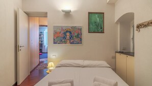 Una habitación de hotel con cama, un cuadro, una lámpara y un armario.