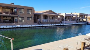 A residential area with a clear water body, houses with balconies, and a flag.