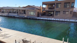 A waterfront property with a pool, outdoor seating, and a two-story building with balconies.
