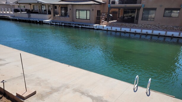 A waterfront property with a swimming pool, a dock, and a house with a balcony.
