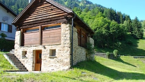 A rustic stone house with a wooden exterior, a sloped roof, and a small front porch.