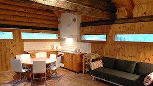 A cozy cabin interior with a dining area, kitchen, and seating space.